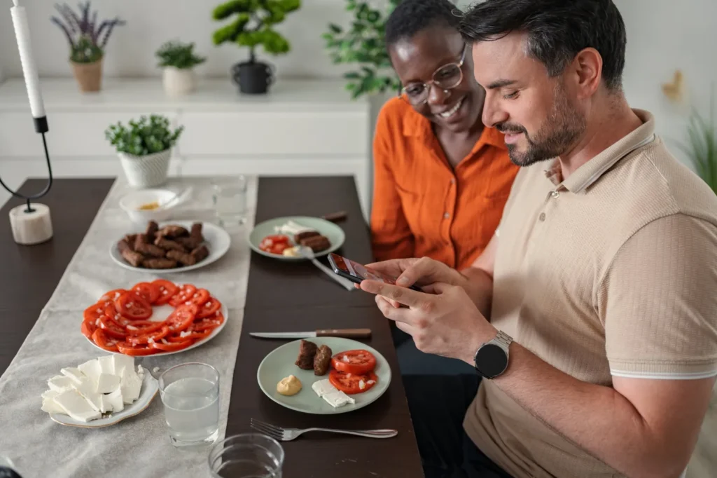 Couple at the dinner table logging their meal in a weight loss tracker app