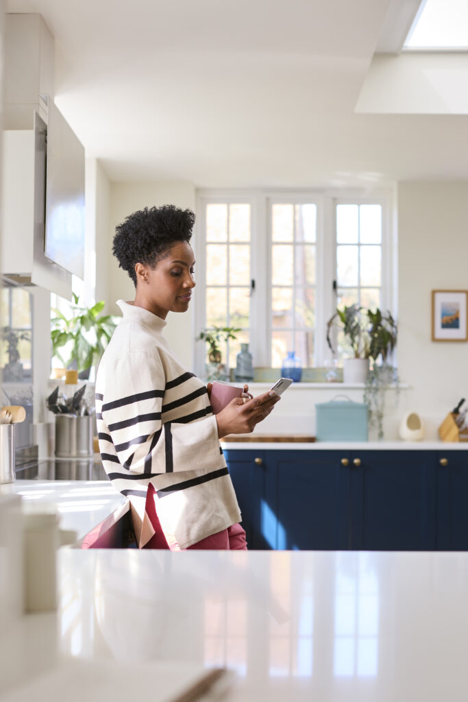 Woman in her kitchen checking her weight loss progress on her phone